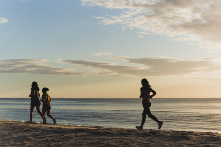 silhouette of three woman jogging on the beach at sunrise.の写真素材