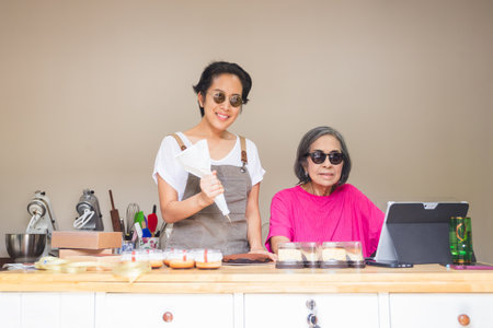 Happy senior mom and adult daughter are preparing pastryの写真素材