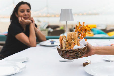 Waitress serving appetizer slice of bread on table for dinner with customer in background.