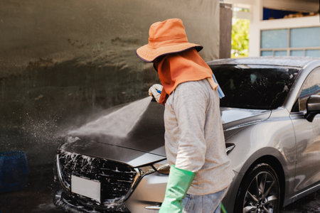 Unidentified man washing car on carwash station using high pressure water.の写真素材