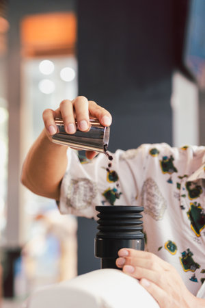 Barista pouring coffee beans into coffee machine tank for grinding in verticalの写真素材