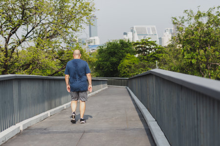 Overweight man exercising walking to burn fat out in city park.の写真素材