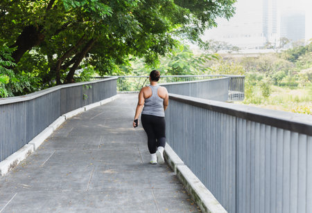 Full length of overweight asian woman walking outdoors on the bridge in city park.