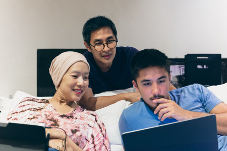 Attractive man looking at laptop in bed with mau and dad.