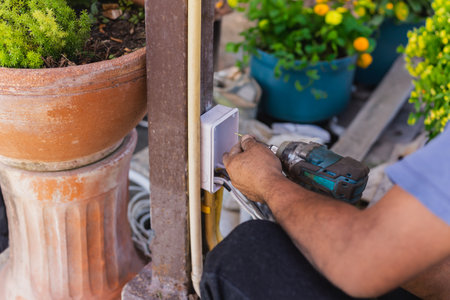 Electrician installing switches and sockets box on the metal pole
