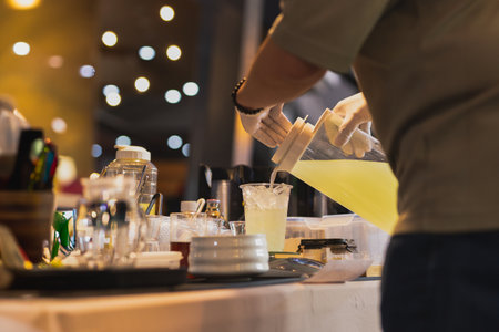 Man pouring juice from jar into a tak away glasses at the shopの写真素材