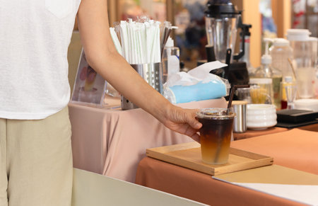 Woman taking iced coffee in a take away cup from cafe counterの写真素材