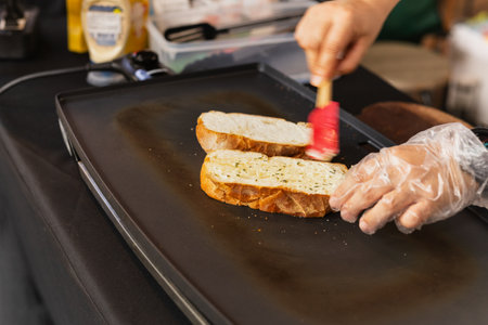 Woman cooking garlic bread with and herbs on iron panの写真素材
