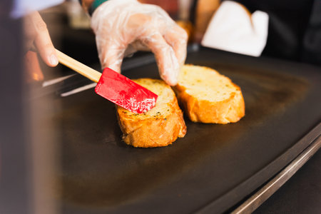 Woman cooking garlic bread with and herbs on iron pan.の写真素材