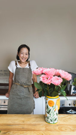 Happy woman in apron at room with flowerの写真素材