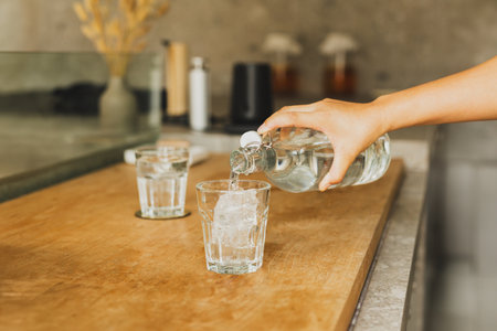 Hand pouring fresh purified water from a bottle into a glassの写真素材