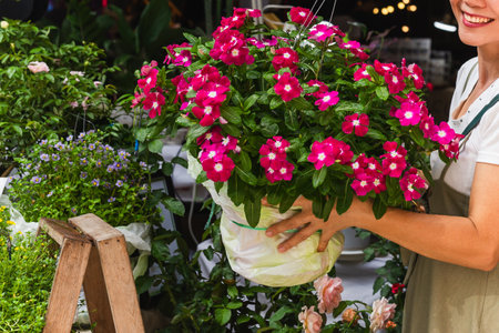 Happy woman holding flowers in big pot at market storeの写真素材