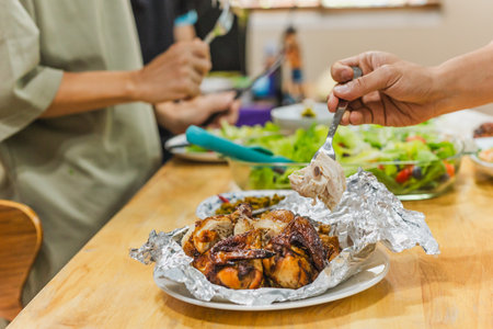 Group of friends enjoying roasted chicken dinner and vegetable saladの写真素材