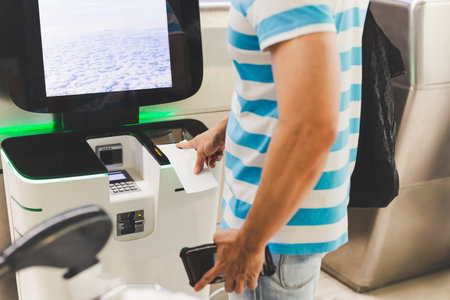 Male passenger doing self check in scanning boarding pass at airportの写真素材