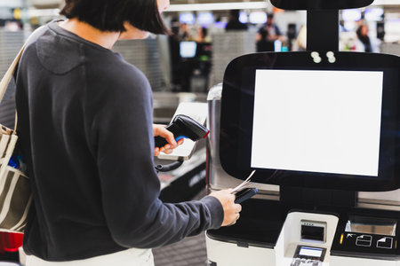 Woman passenger self check in scanning qr code boarding pass at airport with scannerの写真素材