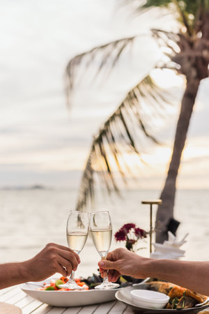 Couple toasting glass of  Champagne at dinner table on teh beachの写真素材
