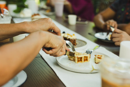 Woman hands cutting waffles with fork and knife on plate in cafe.
