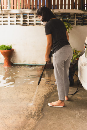 Woman cleaning concrete floor with high pressure jetの写真素材