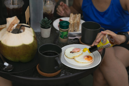 Female friend having breakfast with  fried eggs and coffee on table