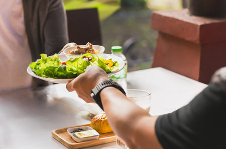 Waiter serving vegetable salad for breakfast in the morningの写真素材