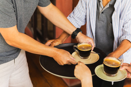 Senior man serving coffee with help of customer at cafeの写真素材