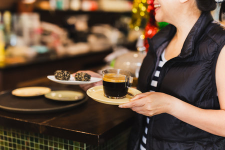 Happy woman holding coffee cup and mini cake at cafeteriaの写真素材