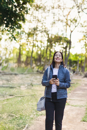 Beautiful asian woman wearing jacket walking outdoors at the parkの写真素材