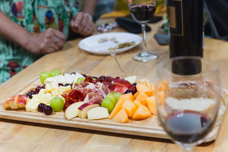Cold cuts smoked ham and Cheese with glasses of red wine on wooden tableの写真素材