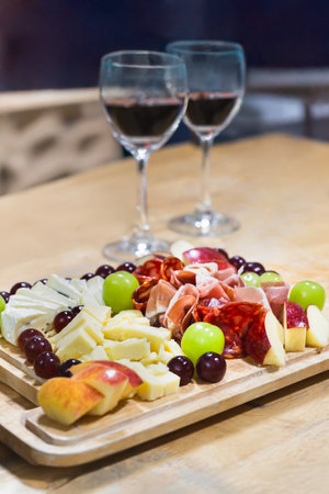 Cold cuts smoked ham and Cheese with glasses of red wine on wooden tableの写真素材