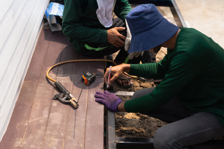 Two builder measures the length of a metal profile with a ruler measure