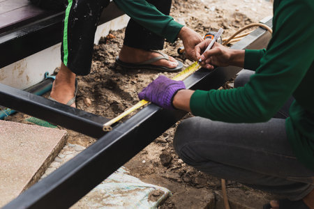 Two builder measures the length of a metal profile with a tape measureの写真素材