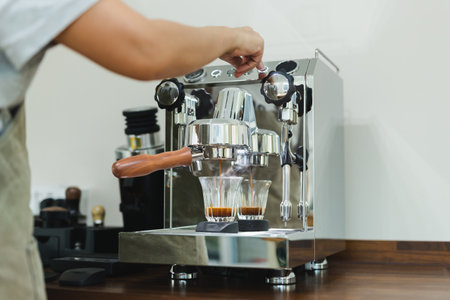 Hands of female barista pressing button on machine while making fresh coffee.の写真素材