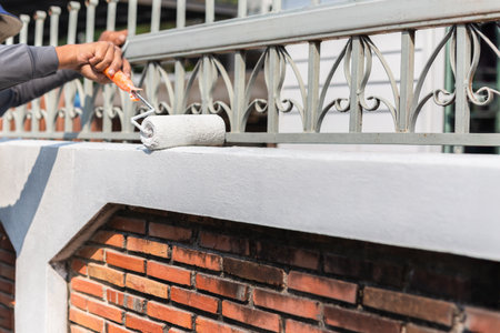 Man painting a wall outside with roller for house decorationの写真素材