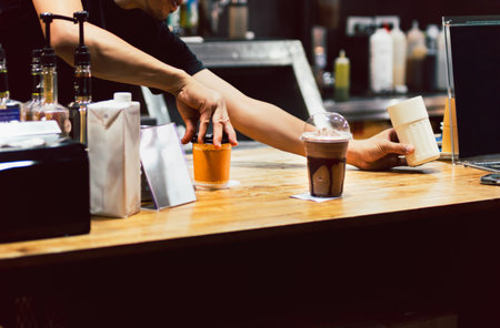 Shot in low light of barista serving a fresh coffee in cafe