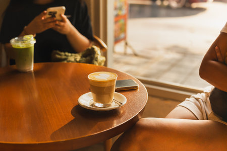 Woman with hot latte glass on the table in cafe with sun lightの写真素材