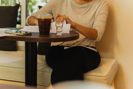 Select focus on Iced black coffee with woman reading documents in cafeの写真素材