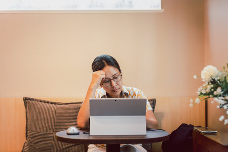 Stressed woman hond holding her head while working on laptopの写真素材