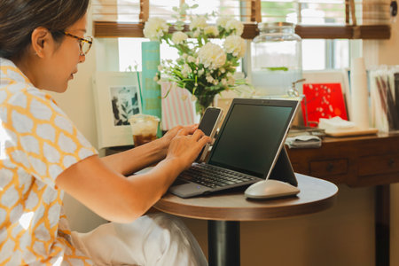 Business woman hands using cell phone while working on laptopの写真素材