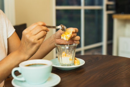 Woman eating an egg with slice of toast in cafe.の写真素材