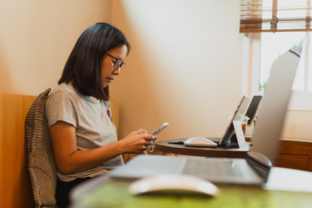 Woman hands using mobile phone while working with laptop in cafe.