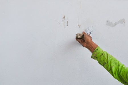 Man hand with trowel plastering a house wall outside.の写真素材