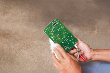 Hand of electrician holding electronic circuit board for repairing.