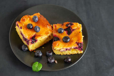 Two pieces of blueberry cake on a dark saucerの写真素材