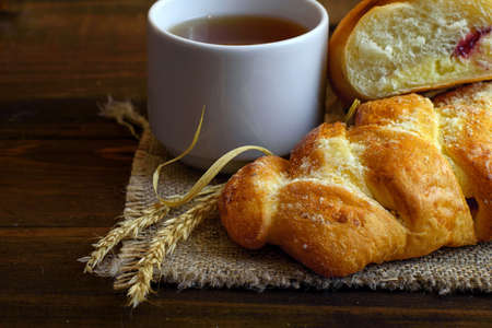 homemade cakes - pastries with cream cheese and strawberry jam and a white Cup of tea on dark wooden...