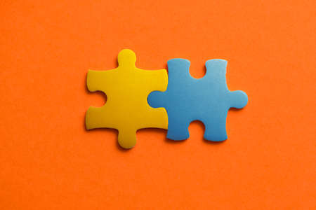 Two colored details of puzzle on orange background, Yellow and Blue, close up.