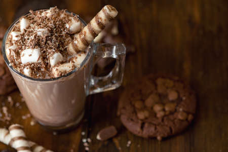 Cup of cocoa with marshmallows and chocolate chip cookies on dark wooden background.の写真素材