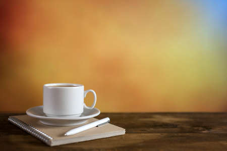 White coffee cup, notepad and pen on colorful background. With copy space.の写真素材