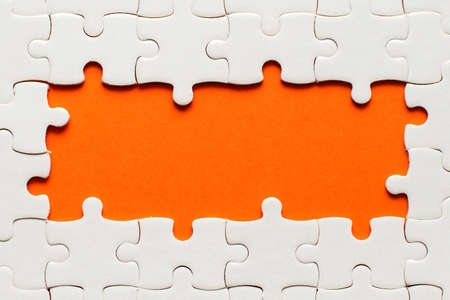 White details of puzzle on orange background and place for inscription.の写真素材