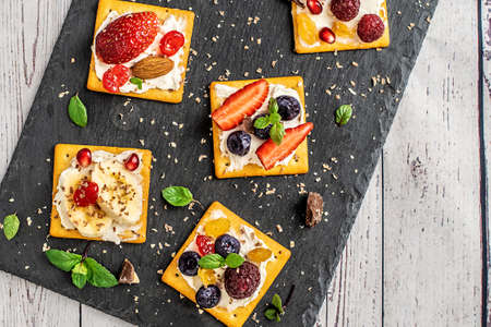 Set of crackers with various fruit close-up on black stone plate.の写真素材