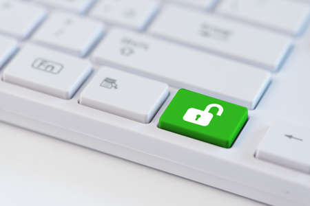 Green key with open padlock icon symbol on laptop keyboard.